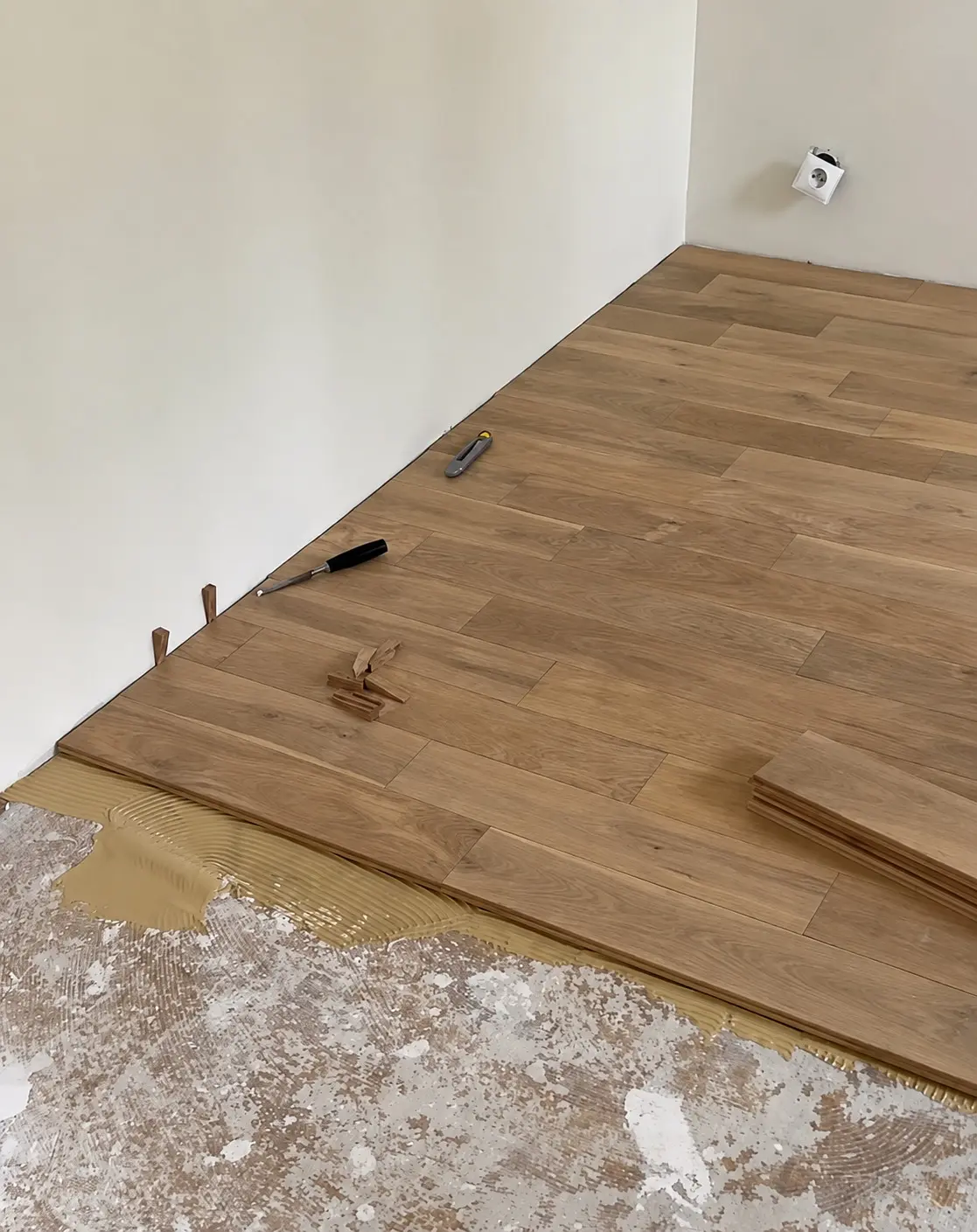 Pose collée de parquet massif en cours dans une chambre à Biarritz